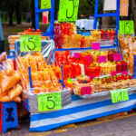 A colorful array of fresh fruits like mango, watermelon, and pineapple displayed at a Mexican street food vendor stall in Mexico City.