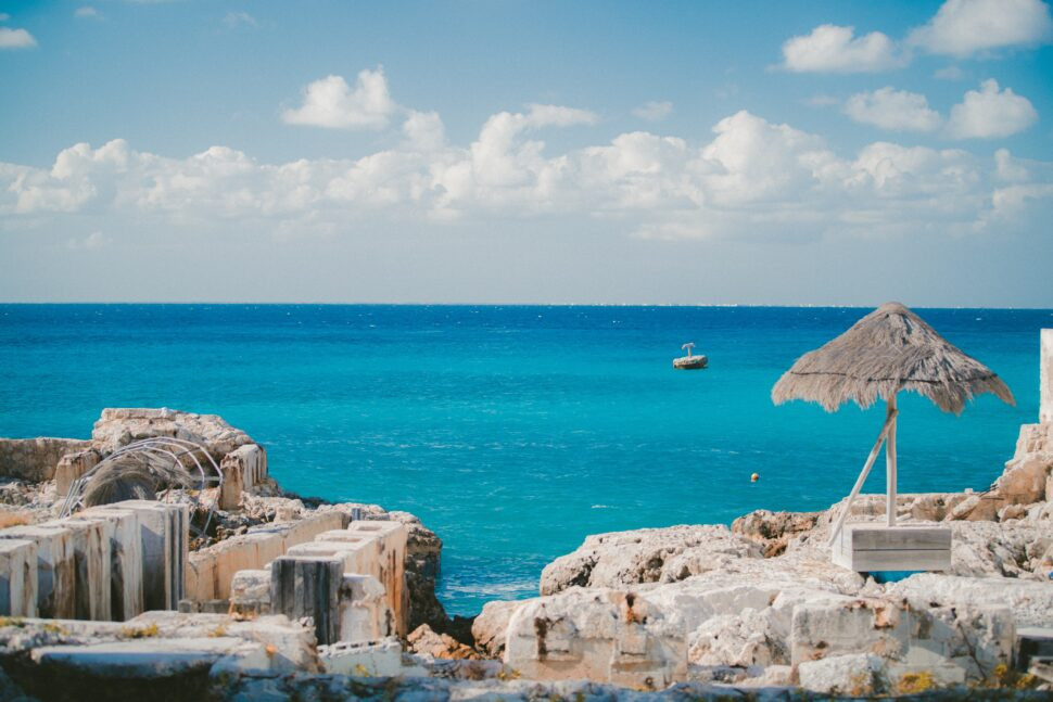 A peaceful shore in Cozumel, Mexico, with a boat in the distance, illustrating the island's safe reputation as a cruise port and tourist-friendly destination