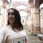 Arched ruins of Spanish Catholic church in original colonial capital of Guatemala in Antigua. Smiling Latina woman Kayley Whalen is wearing a