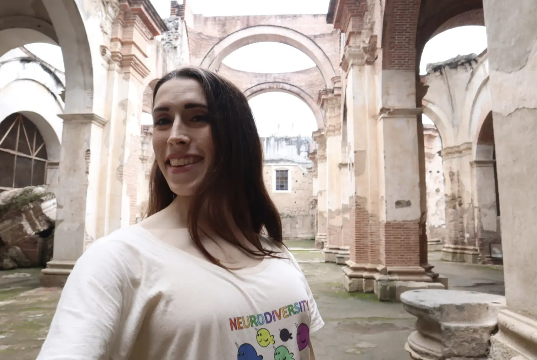 Arched ruins of Spanish Catholic church in original colonial capital of Guatemala in Antigua. Smiling Latina woman Kayley Whalen is wearing a