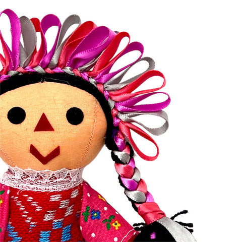 A detailed shot of a small Lelé doll showcasing its traditional clothing and embroidered details