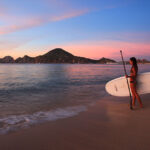 Tourists enjoying a sunny day at Medano Beach, a popular spot for swimming and socializing in Cabo San Lucas.