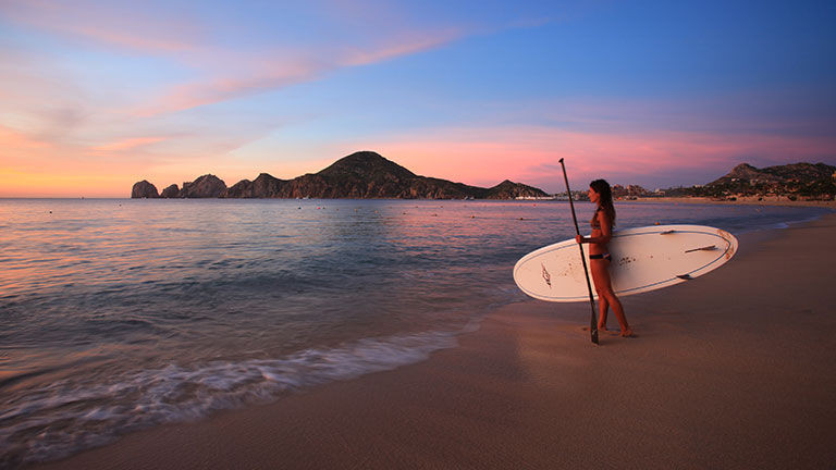 Tourists enjoying a sunny day at Medano Beach, a popular spot for swimming and socializing in Cabo San Lucas.