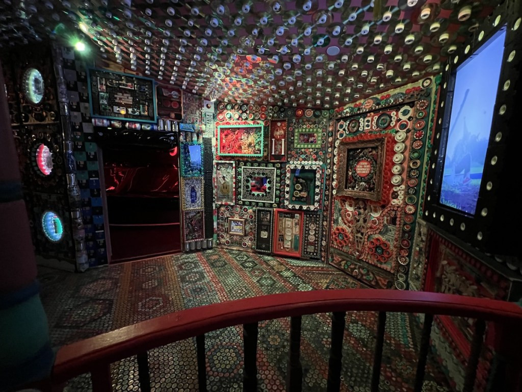 A room decorated magnificently as a mosaic of assorted items like bottle caps, CDs, and cellphones.