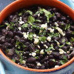 A delicious bowl of Mexican black beans topped with cotija cheese, showcasing a classic and flavorful side dish.