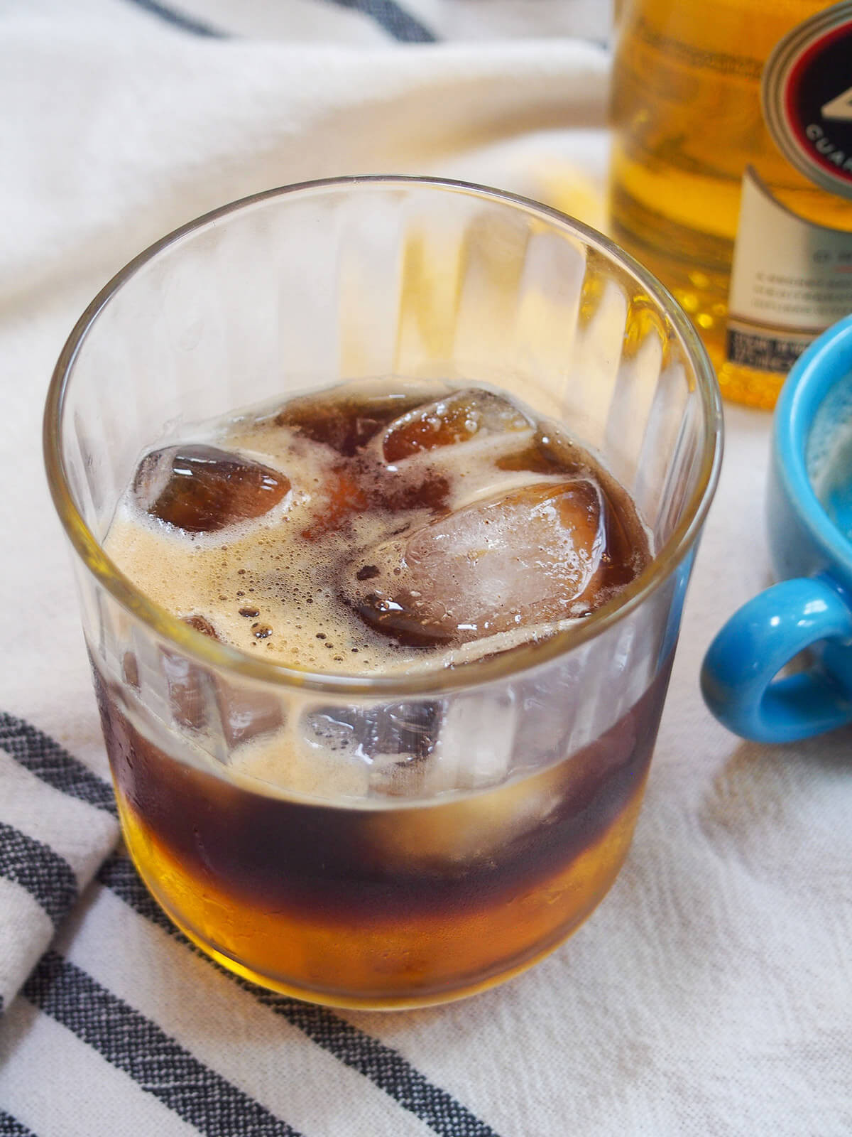 Close-up view into a glass of Mexican carajillo coffee cocktail, emphasizing the inviting color and texture of the drink.