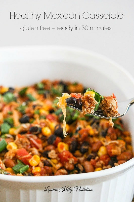 Close up of a fork scooping healthy Mexican casserole from a white dish, recipe title visible above.