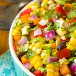A vibrant turquoise bowl filled with Mexican Chopped Salad, showcasing the colorful vegetables and dressing.