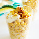 A close-up shot of esquites, Mexican corn in a cup.