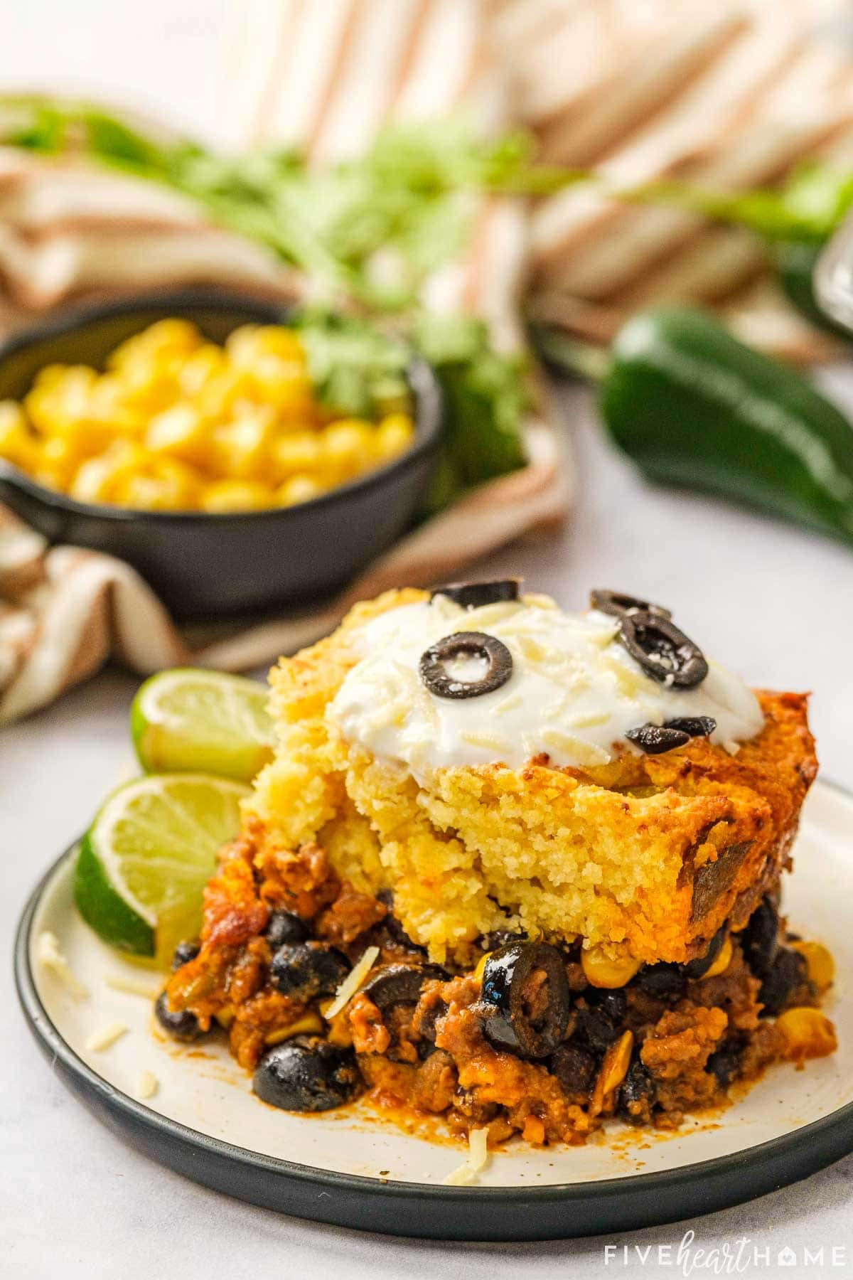 A slice of Mexican Cornbread Casserole plated and ready to eat, with a side of lime wedges for garnish.