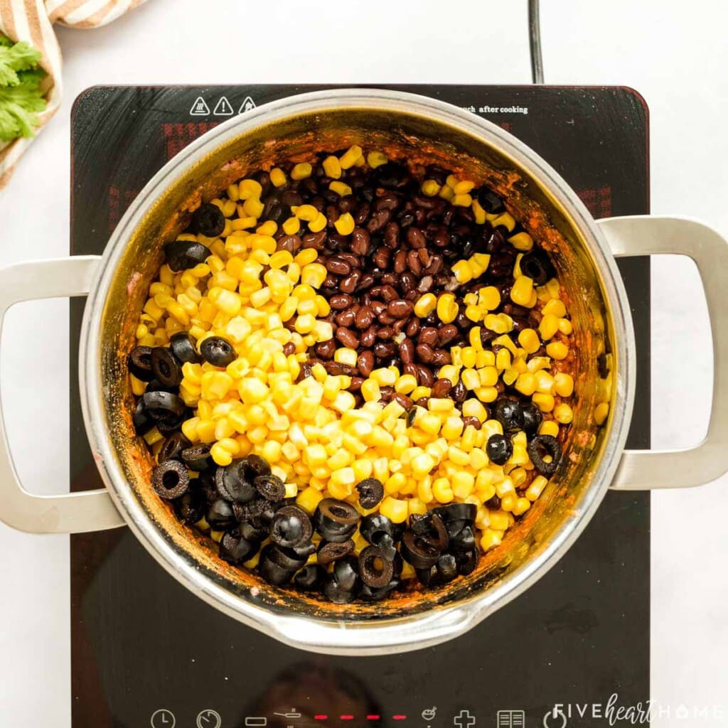 Black beans, corn, and black olives being added to the ground beef mixture in a pot.