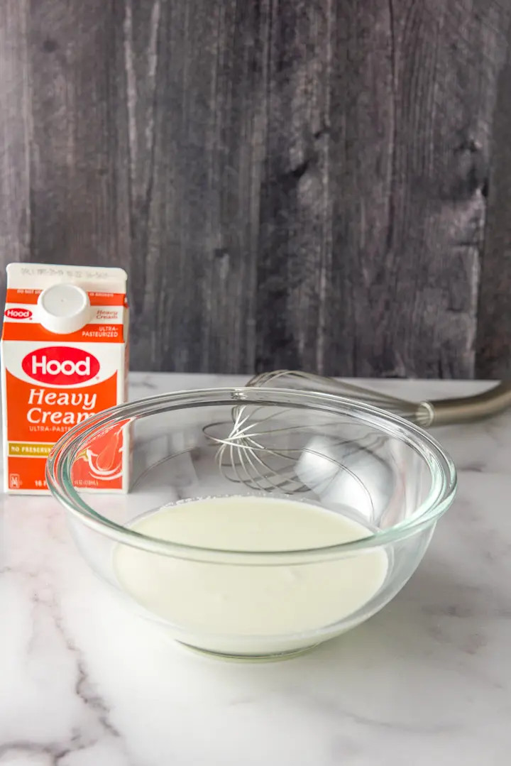 Cream poured in the bowl and a whisk in the background