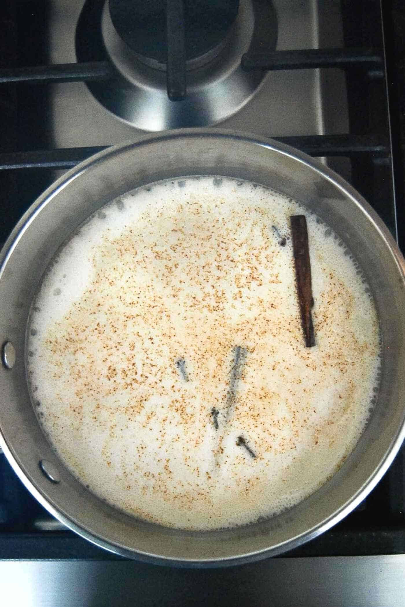 milk, cinnamon sticks, chocolate and cocoa on stove for mexican hot chocolate