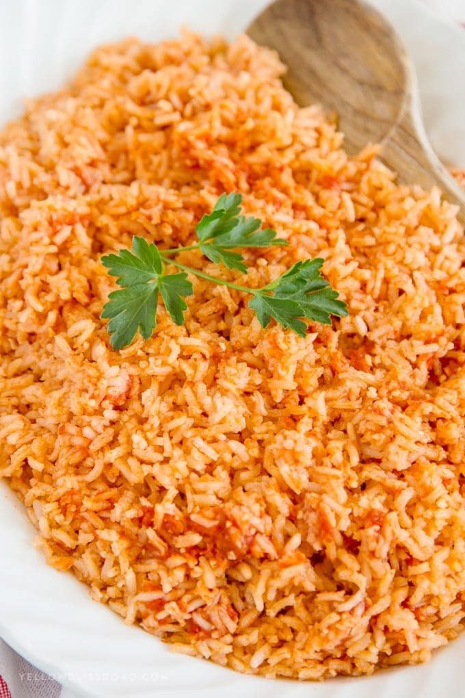 Authentic Mexican Rice recipe beautifully plated on a white platter with a sprig of parsley, ready to serve