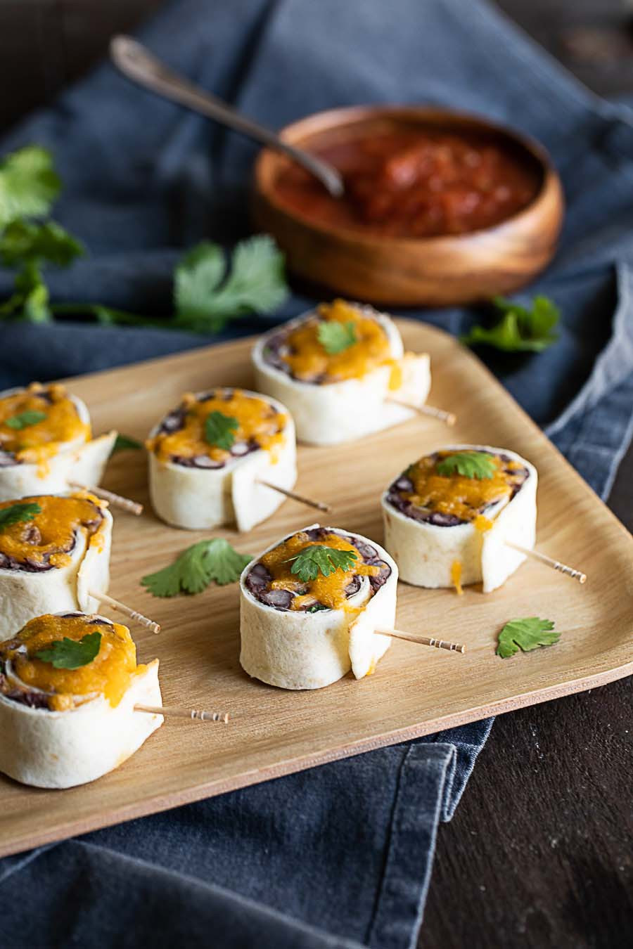 Side view of a plate of Mexican Pinwheels, showcasing their rolled tortilla layers and cheesy topping, ideal as party-ready Mexican food horderves.