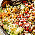 Close-up of vibrant Mexican Salad ingredients in a wooden bowl, featuring corn, avocado, tomatoes, and radishes