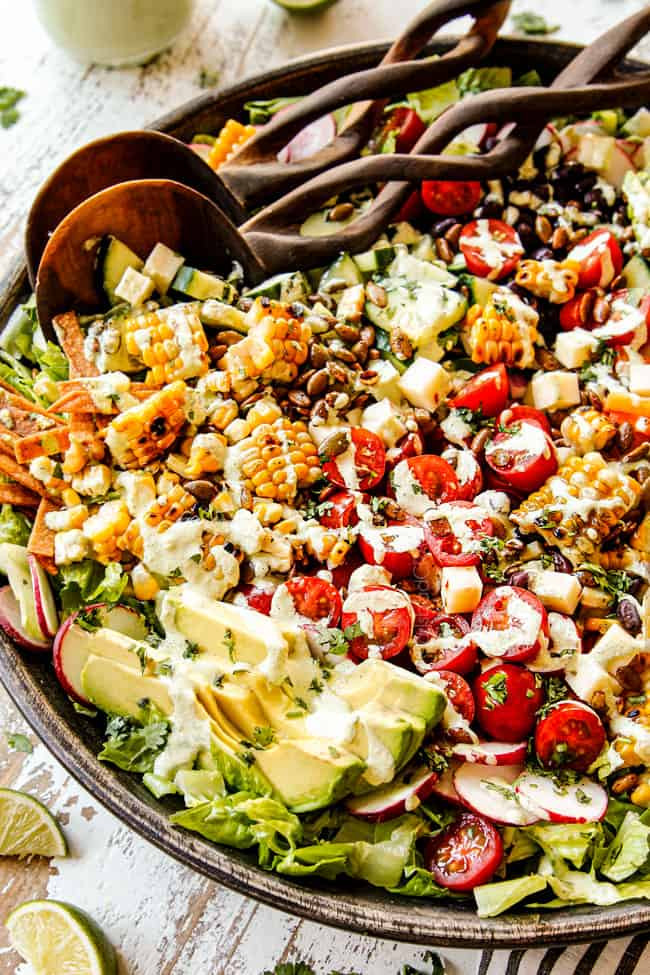 Close-up of vibrant Mexican Salad ingredients in a wooden bowl, featuring corn, avocado, tomatoes, and radishes