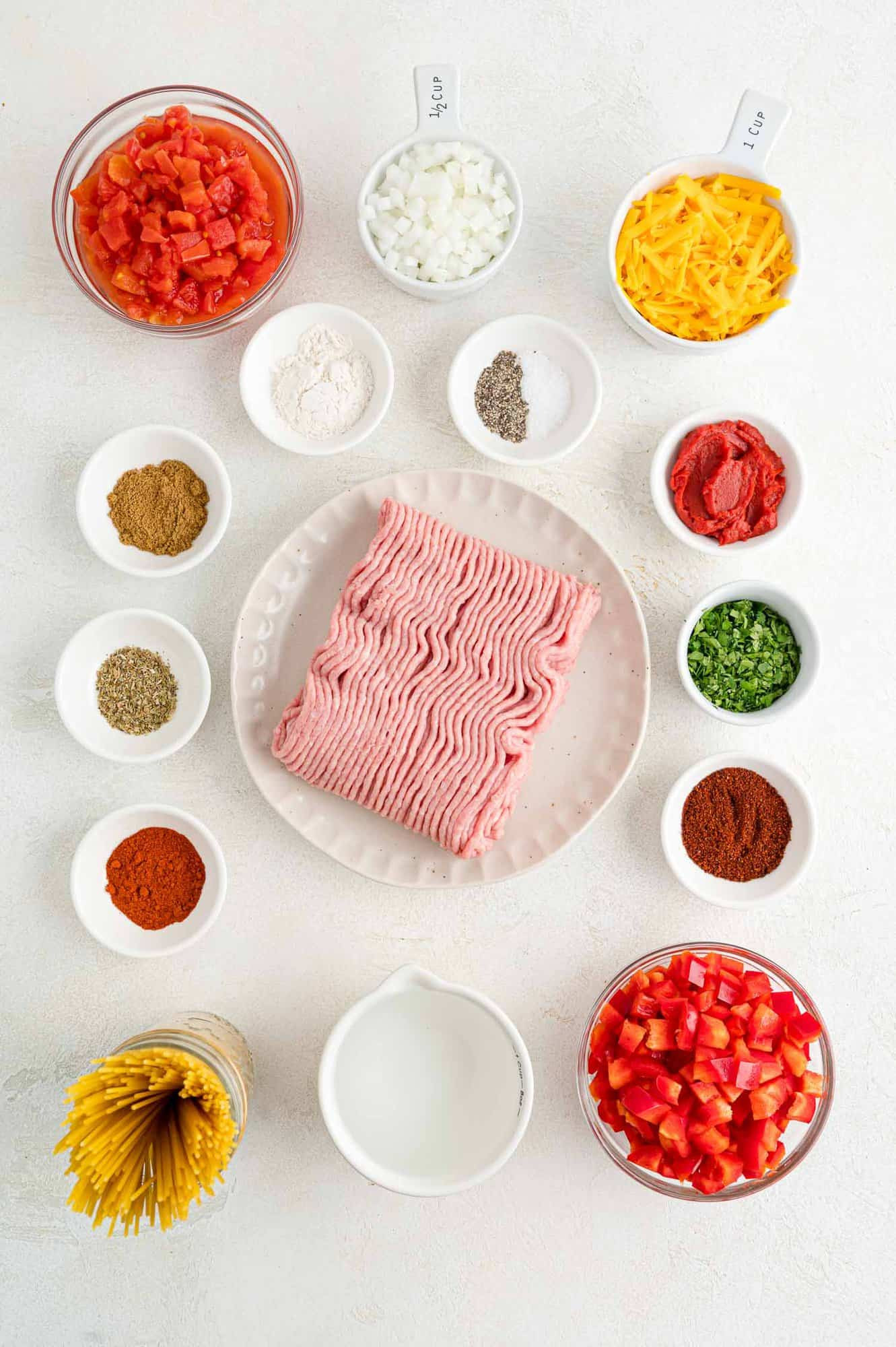 Image showcasing the key ingredients for Mexican Spaghetti, including ground turkey, vegetables, spices, and pasta, laid out for preparation.