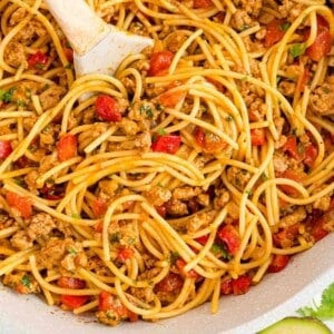 Square image of One-Pot Mexican Spaghetti in a skillet with a serving spoon, showcasing the recipe's ease and presentation.