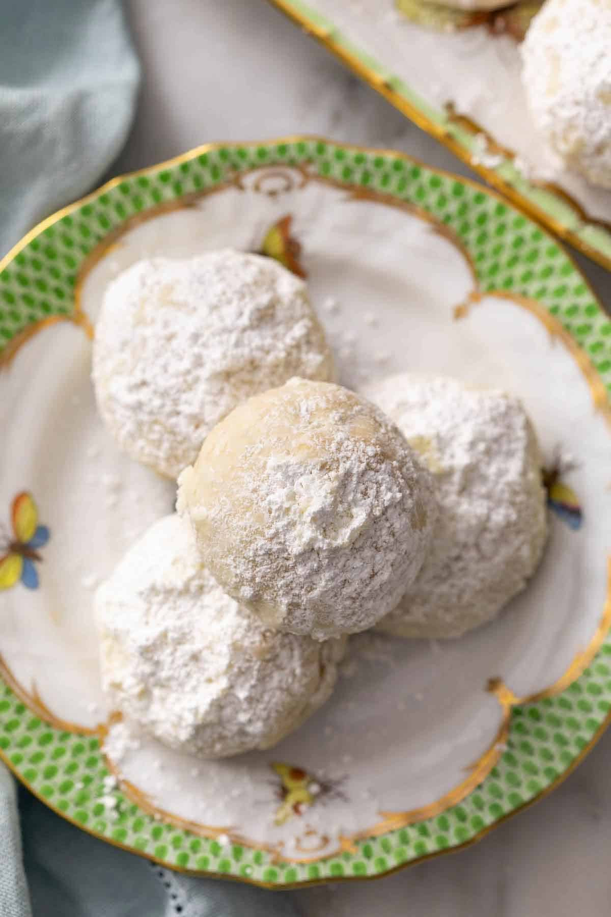 A small plate with a pile of Mexican wedding cookies, showcasing their snowy powdered sugar coating.