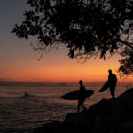 Two surfers head to the ocean at sunset in Mexico
