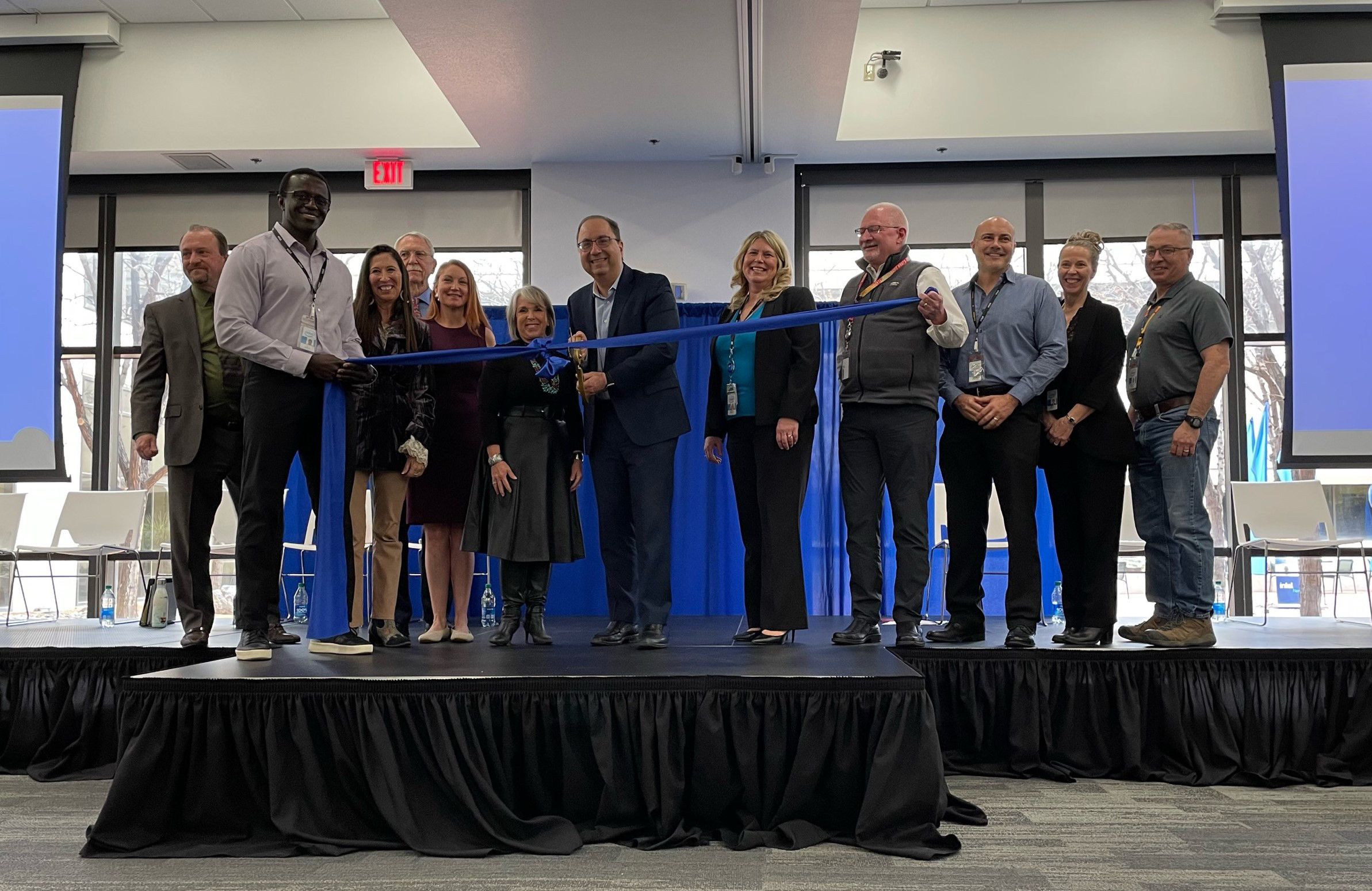Ribbon-cutting ceremony for Intel Fab 9 in Rio Rancho, New Mexico, featuring Keyvan Esfarjani, local officials, and Intel managers celebrating the facility opening.