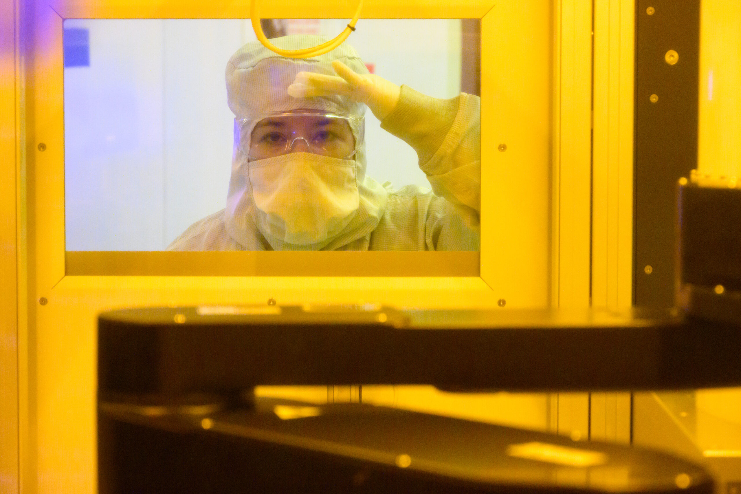 Intel technician in a cleanroom suit inspecting advanced packaging equipment at Fab 9, Rio Rancho, New Mexico, emphasizing precision and technological advancement.