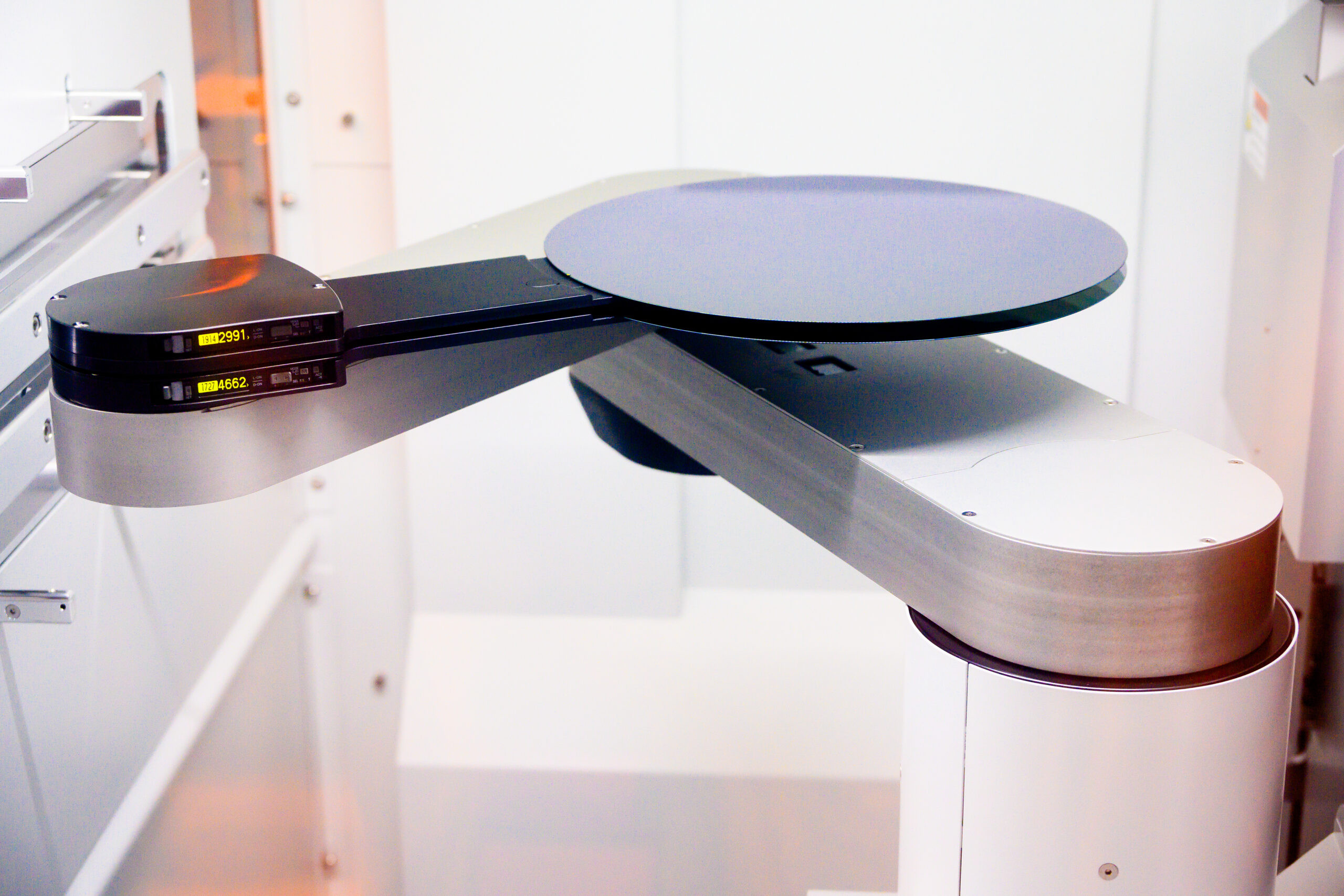 Robotic arm handling a silicon wafer in the automated manufacturing environment of Intel's Fab 9, Rio Rancho, New Mexico, highlighting automation in semiconductor production.