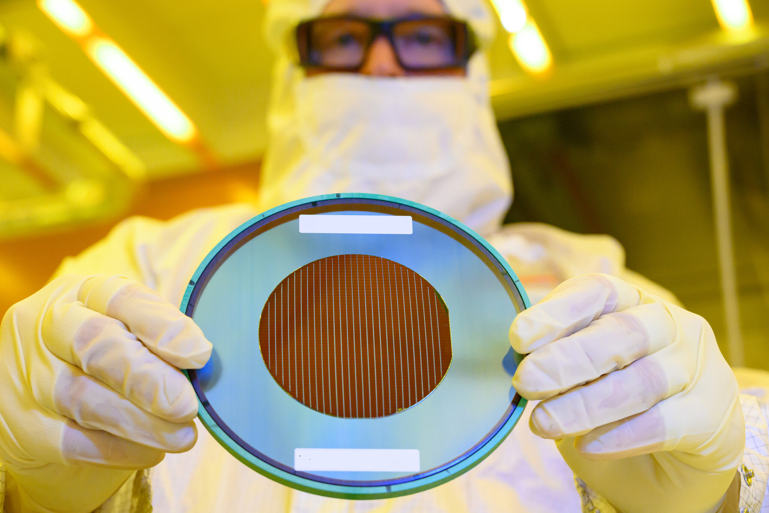 Technician holding a silicon wafer in a cleanroom at Intel New Mexico, displaying the advanced materials and technology in semiconductor manufacturing.