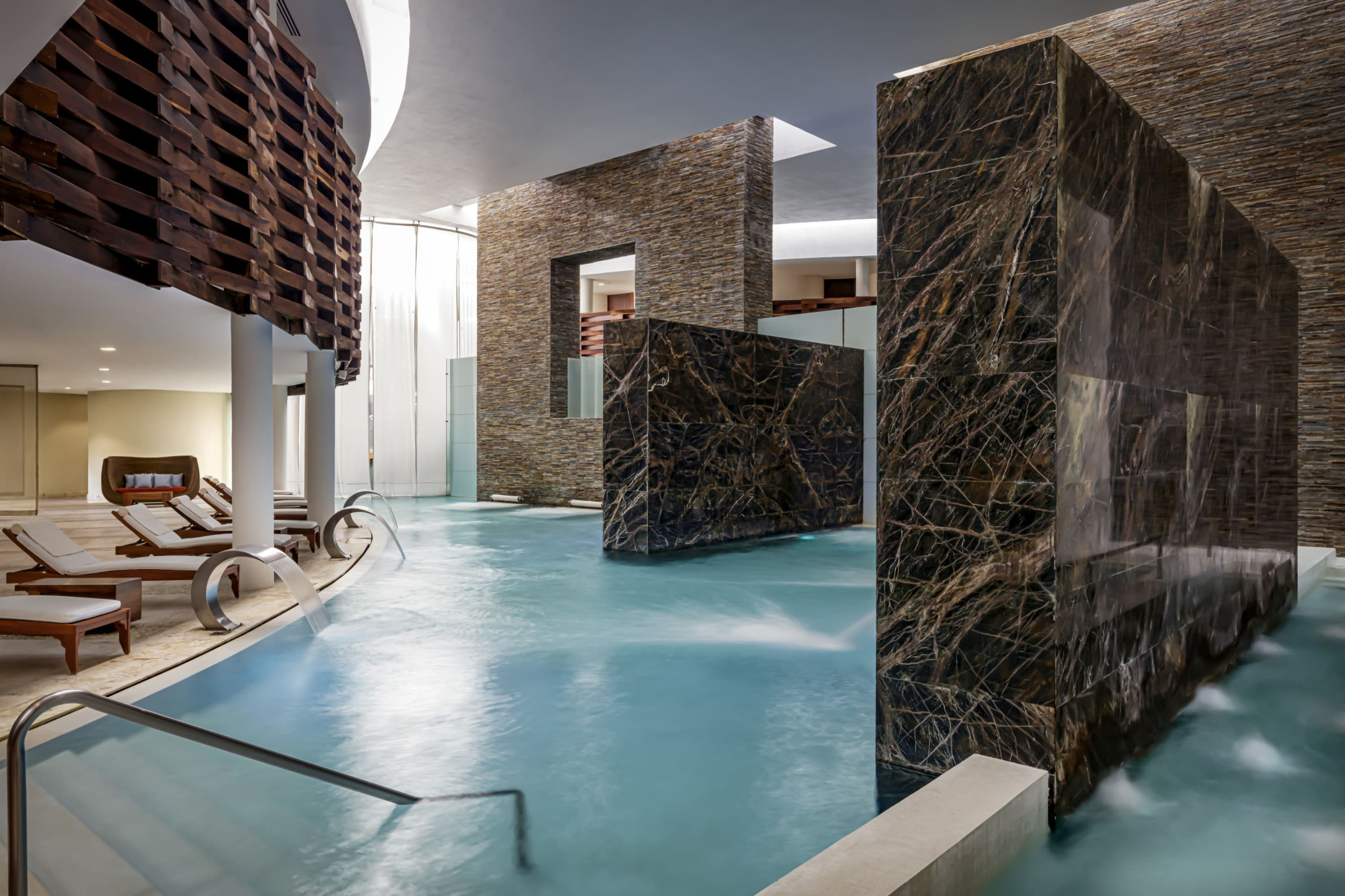 Chic pool area with marble walls and steam rising up from the water