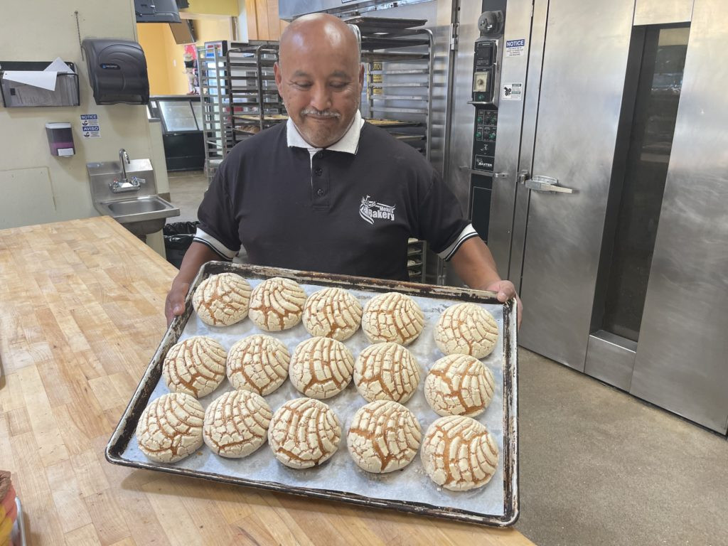 Melchor Landin holding a tray of freshly baked conchas at Mexico Bakery.