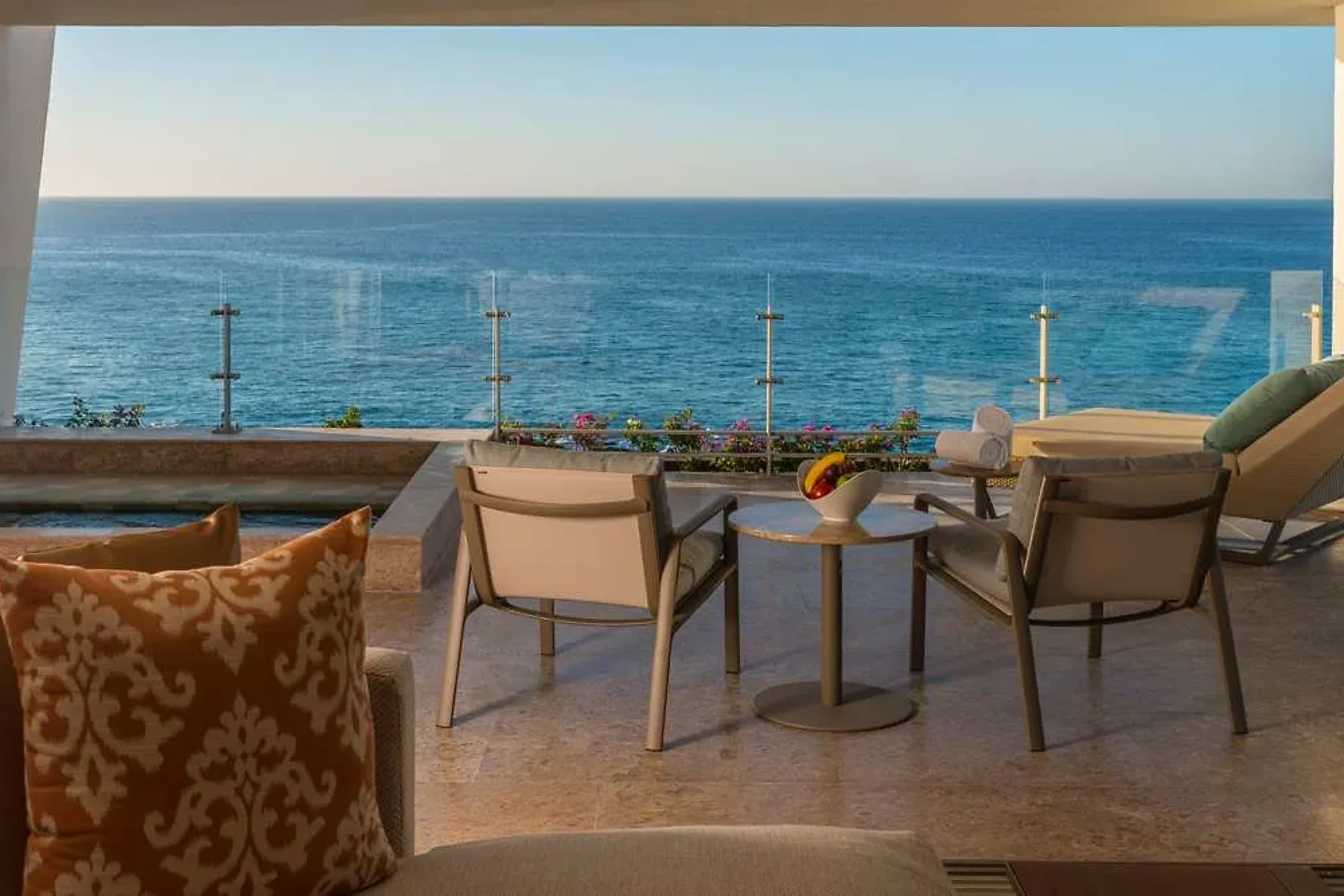 A private pool is mostly obscured by a outdoor sofa and two lounge chairs are positioned to look out over the ocean