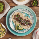 Vibrant plates of tacos on a wooden table at Los Galanes Mexican Restaurant, a top dining destination in Detroit.