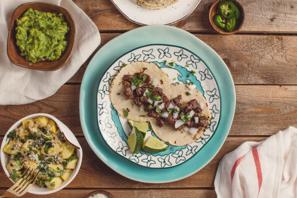 Vibrant plates of tacos on a wooden table at Los Galanes Mexican Restaurant, a top dining destination in Detroit.