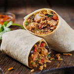 A hearty burrito filled with rice, chorizo sausage, black beans, roasted peppers, and cilantro, a staple in Mexican cuisine