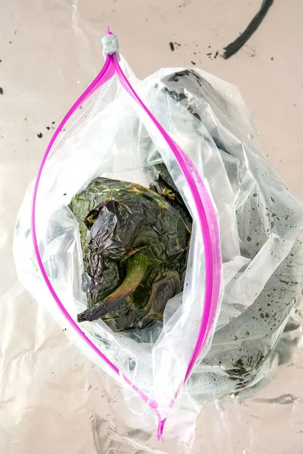 Roasted poblano peppers steaming in a ziplock bag, illustrating the steaming process to facilitate peeling