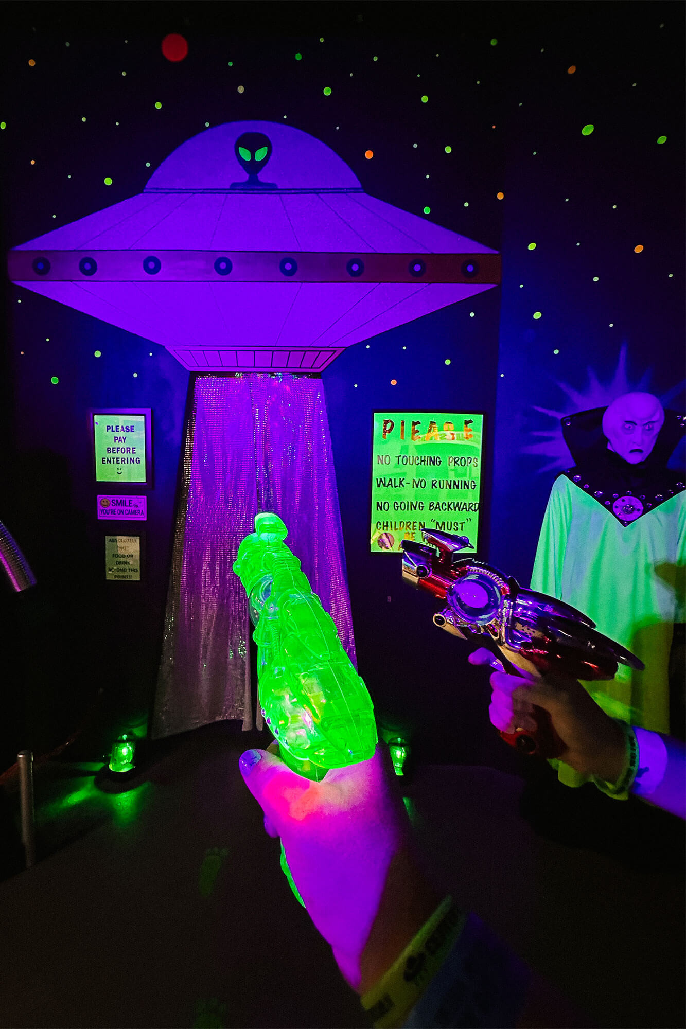 Two hands hold glow-in-the-dark toy guns pointed at a UFO inside the UFO Spacewalk attraction in Roswell, New Mexico