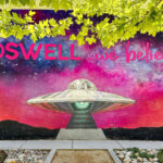 A colorful mural featuring the words "Roswell We Believe"