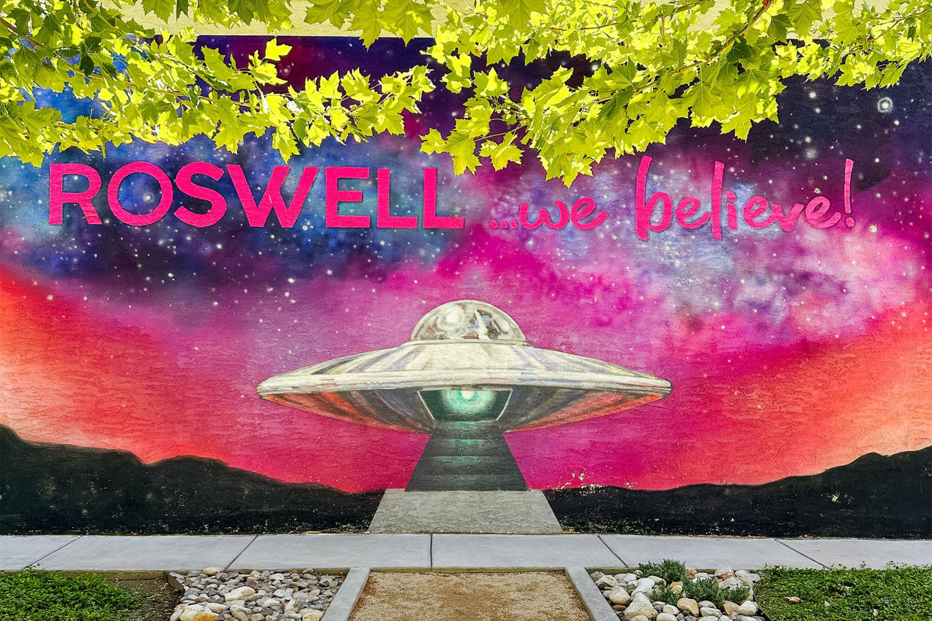 A colorful mural featuring the words "Roswell We Believe"