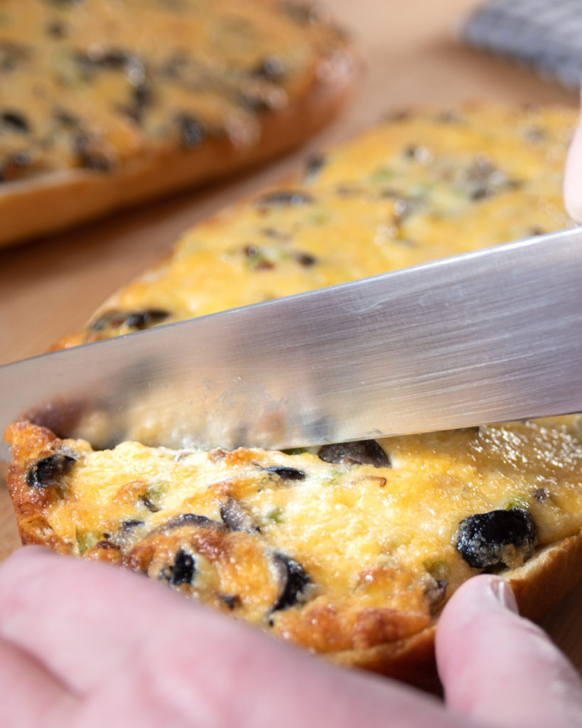 Slicing a piece of cheesy Mexican Garlic Cheese Bread to serve