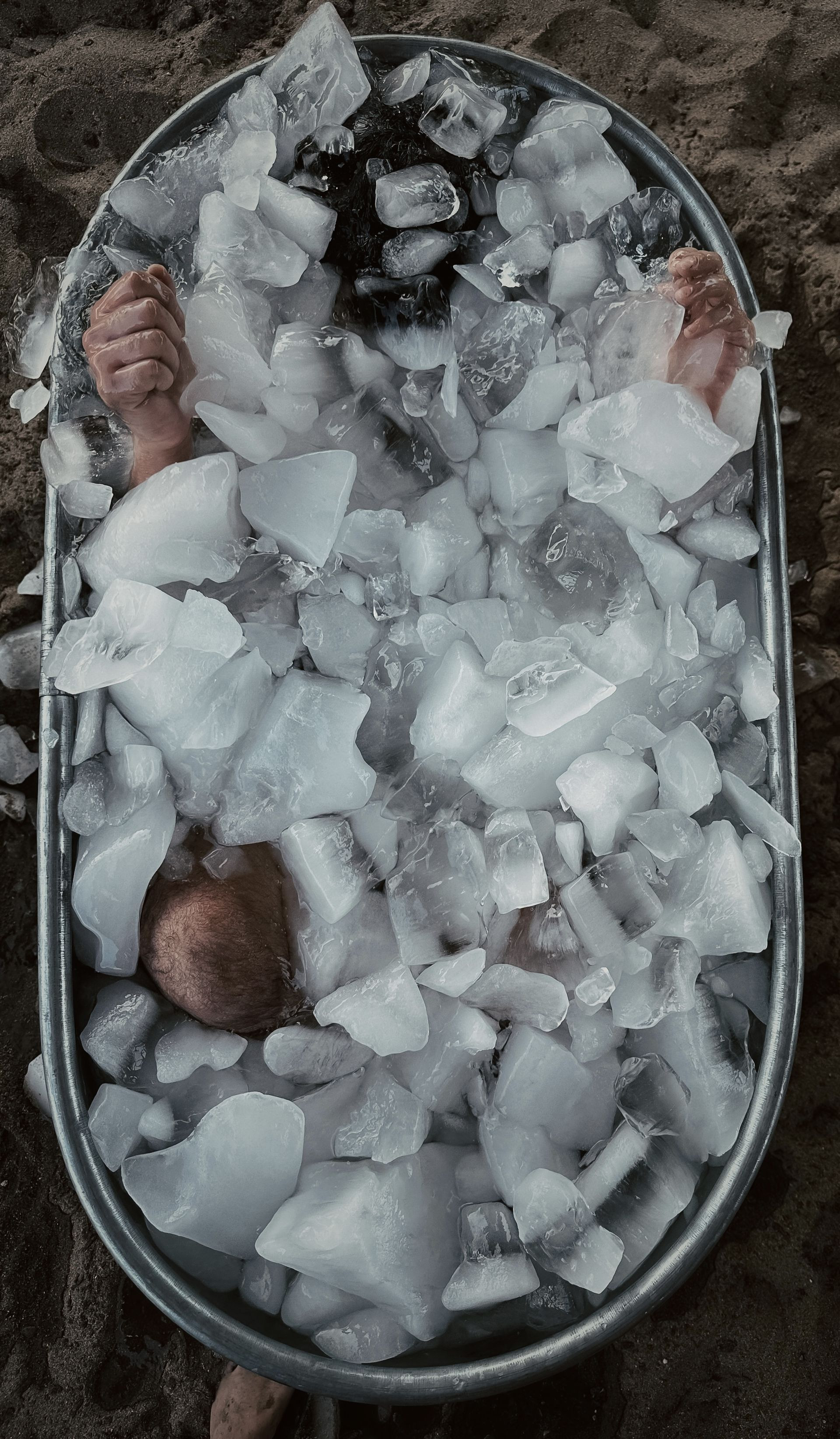 Person immersed in an ice bath at El Club Del Hielo in Mexico City, showing hands and knees above the ice