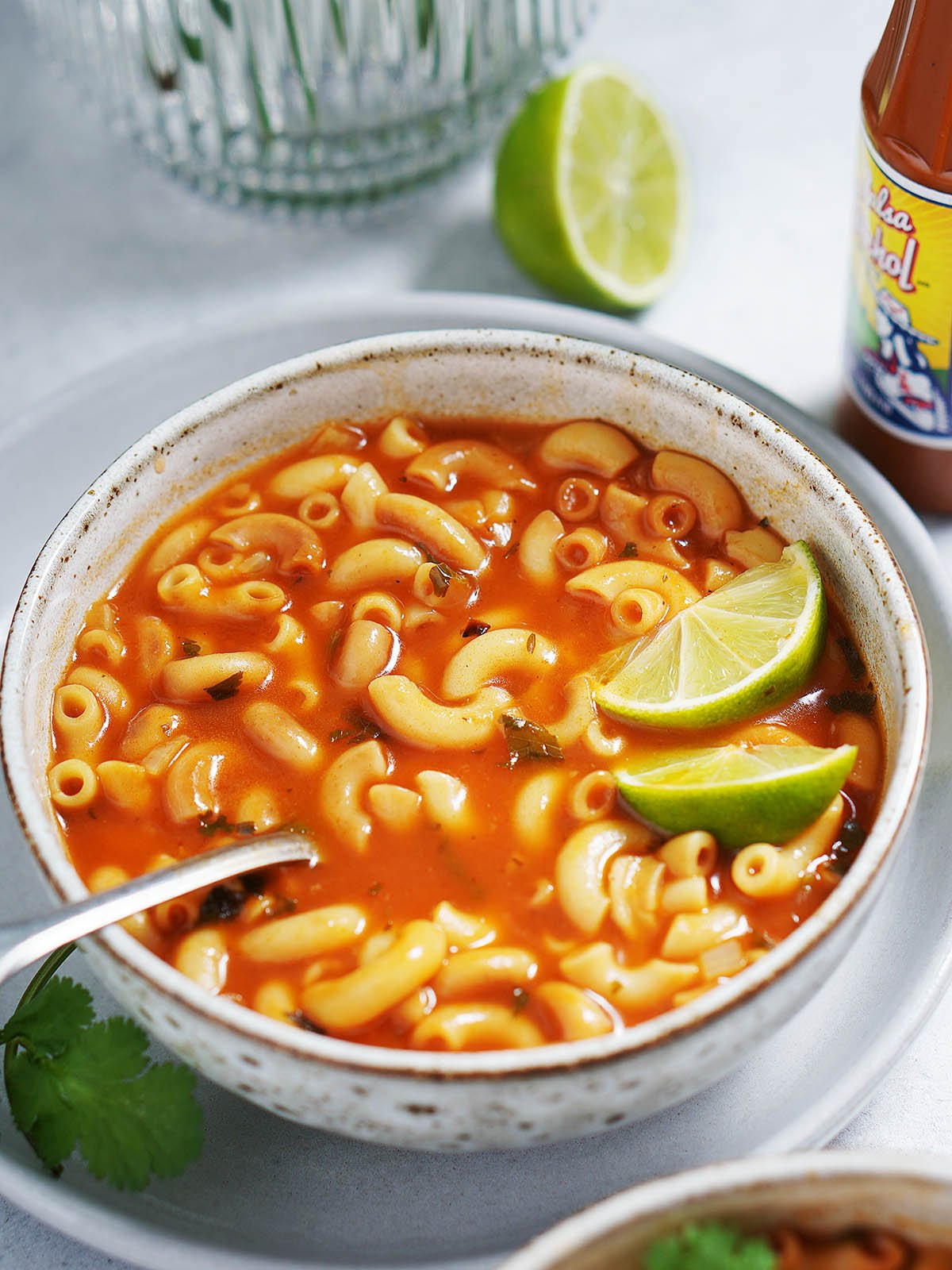Close up of a bowl of mexican sopa showing the rich red broth and noodles.