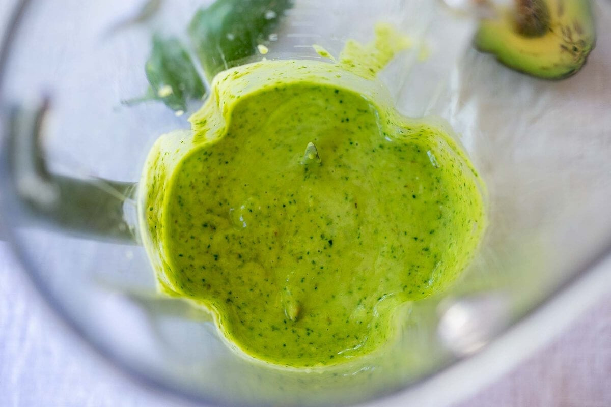 Creamy avocado sauce being blended in a glass blender.