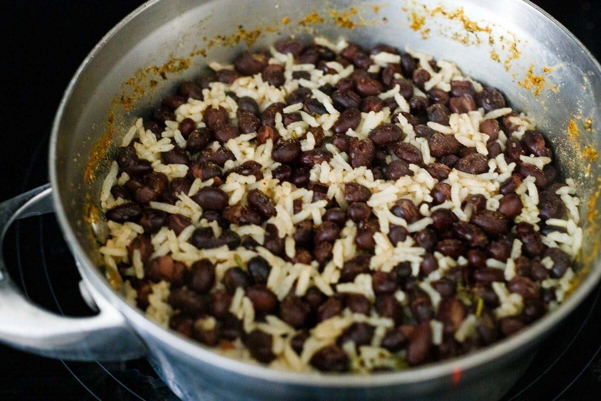 Cooked rice and beans in a pot with visible spices mixed in.