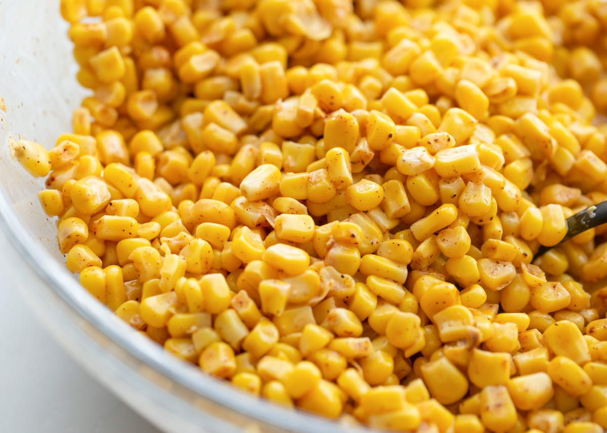 Ingredients for Mexican street corn mixed together in glass bowl.