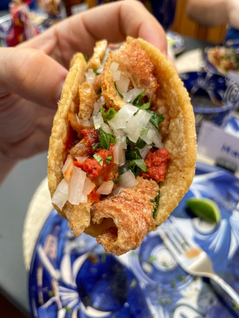 A close-up of hands preparing tacos during a cooking class, showcasing fresh ingredients.