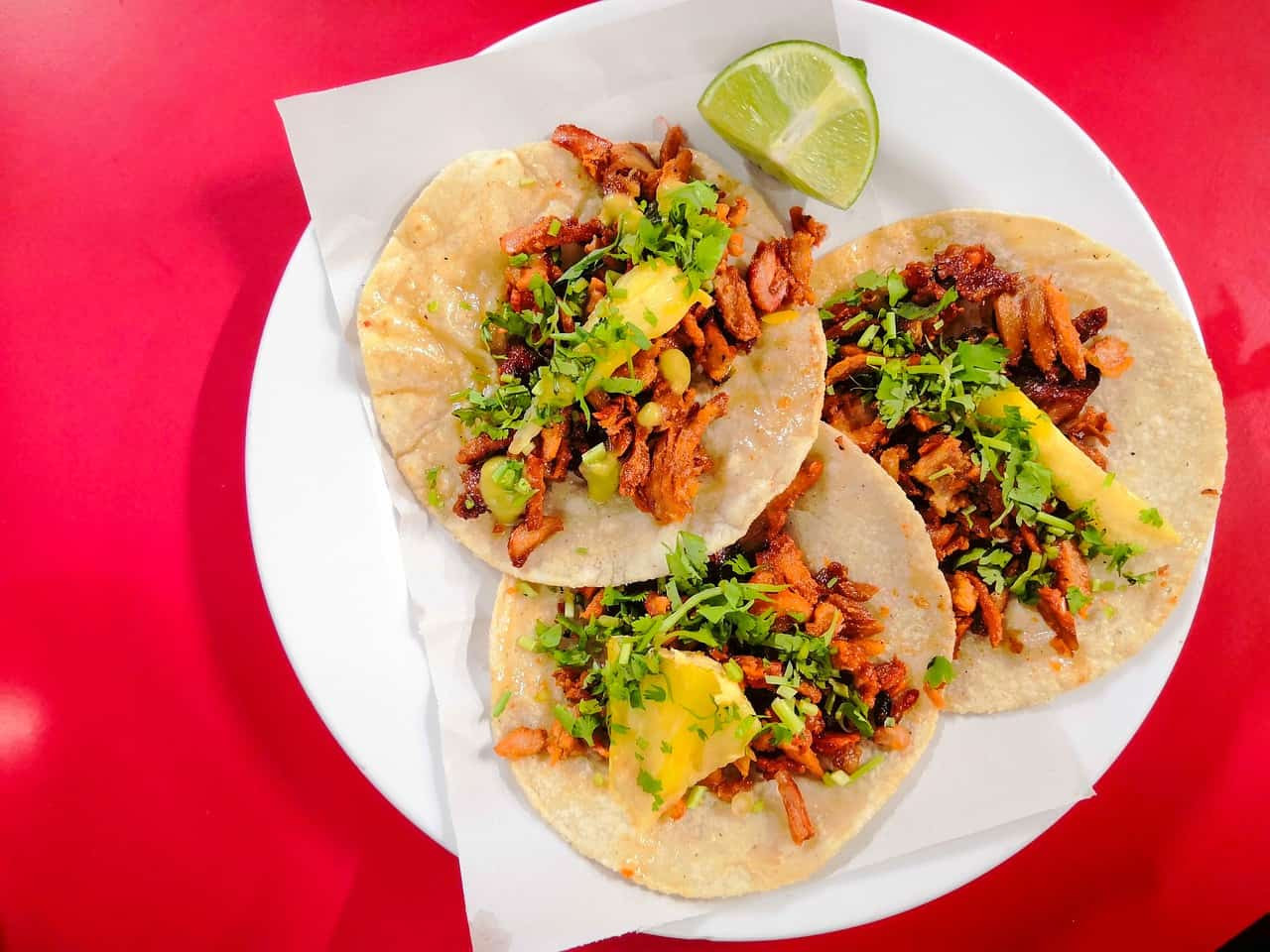 3 tacos al pastor on a red plate