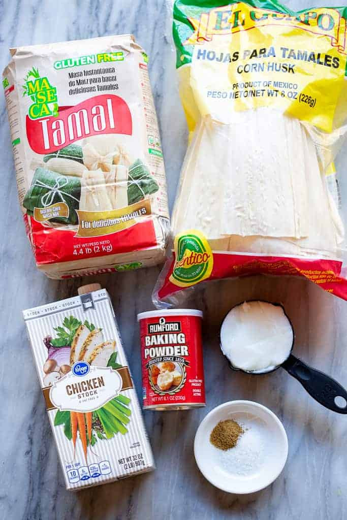 Ingredients for tamales including masa harina, corn husks, lard, broth, baking powder and spices.