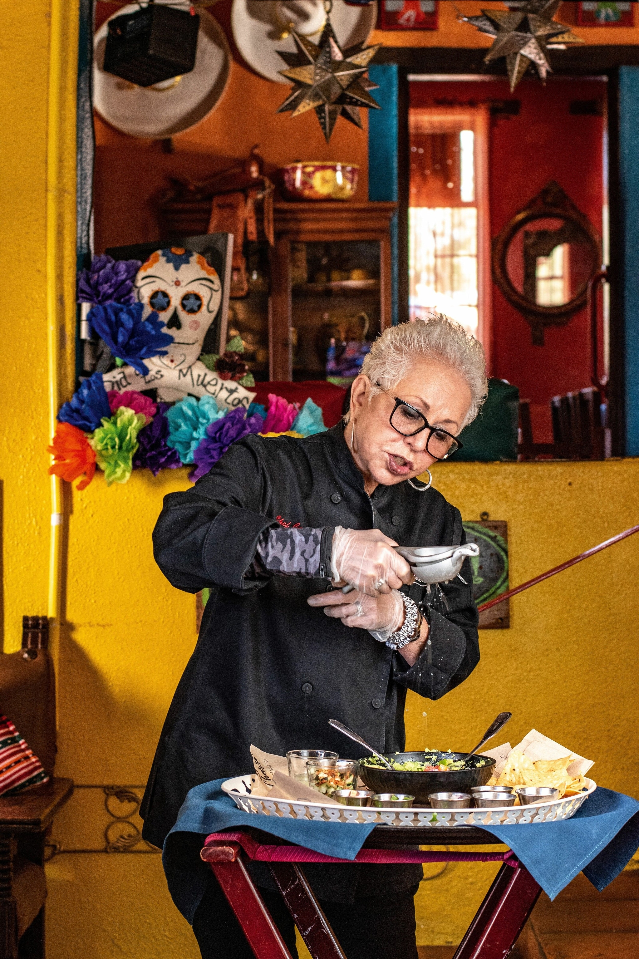 Chef Carlotta Flores preparing guacamole at El Charro Cafe, demonstrating culinary expertise and tradition.