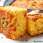 Two slices of Mexican cornbread on a plate with a dab of butter on top of one.